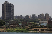 A general view of a farmland with houses on small island next to crowded residential buildings and bridges on the bank of River Nile, in Cairo