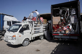 Syrian returnee Ahmed Al-hadid, and his family members load belongings to a truck, in Aleppo's countryside