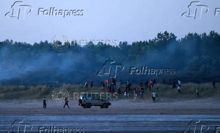 Police use tear gas to disperse a group of migrants trying to cross the beach to reach a dinghy whilst trying to cross the English Channel on a beach at Gravelines