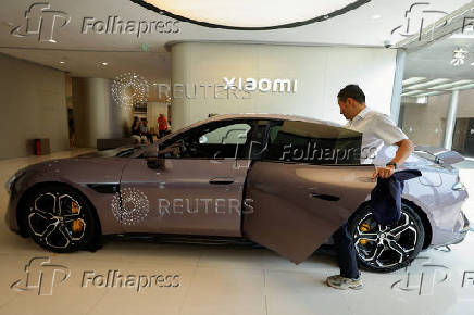 Person tries the electric sedan SU7 displayed at a Xiaomi store in Beijing