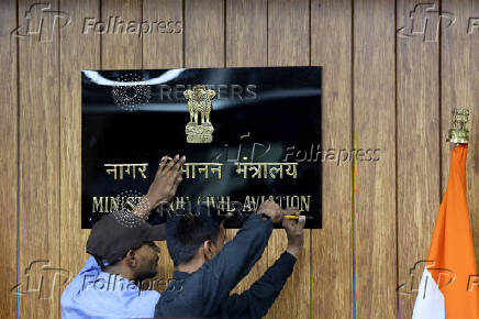 Workers put up a signage of the ministry of civil aviation before the start of a press conference in New Delhi