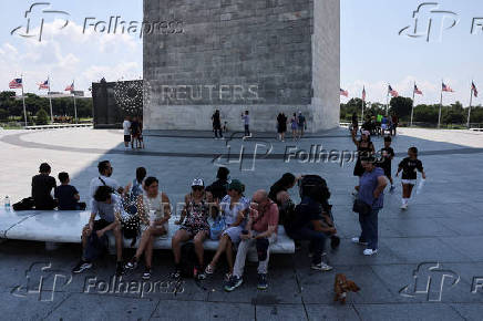 Tourists seek relief in the shade created by the Washington Monument during a heatwave affecting the eastern U.S., in Washington