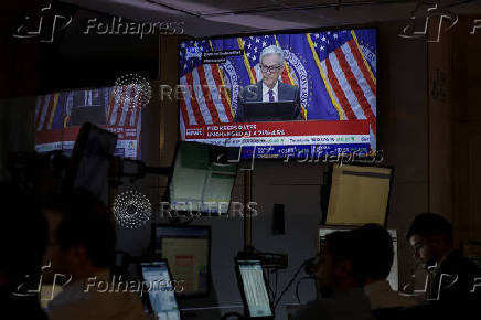 Traders work, as a screen broadcasts a press conference by U.S. Federal Reserve Chair Jerome Powell following the Fed rate announcement, on the floor of the NYSE in New York