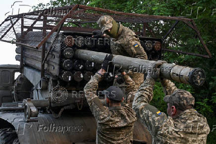 Ukrainian servicemen load a rocket into a multiple launcher before firing towards Russian troops on a front line in Zaporizhzhia region