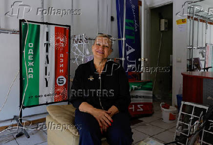 A shop owner shows the damage to her store following the shelling of a market in Donetsk
