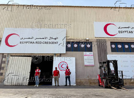 People stand in front of a warehouse for aid deliveries, outside Arish