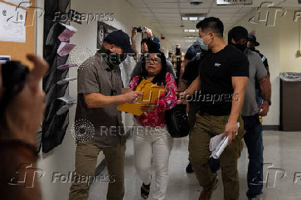 A migrant is detained by federal immigration officers at U.S. immigration court
