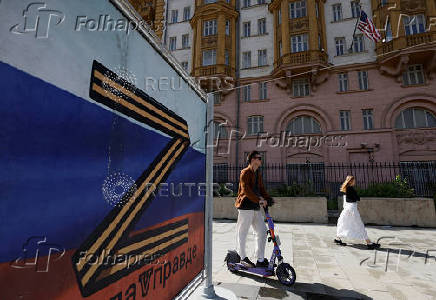 People walk past a banner depicting the symbol 