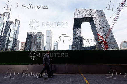 Cleaner walks past buildings at Central Business District (CBD) in Beijing