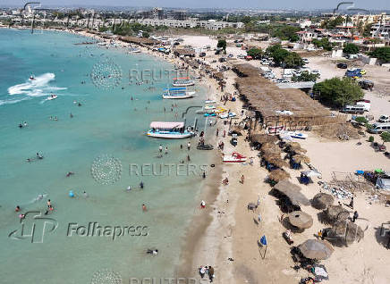 A drone view shows people swimming at a public beach in Latakia
