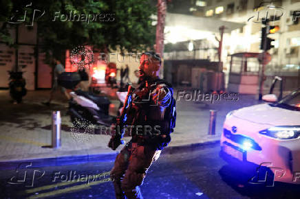 Security personnel react at an impact site following a missile attack from Iran on Israel, at Tel Aviv