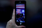 FILE PHOTO: A person shoots video on their smartphone of Republican presidential nominee Donald Trump as he speaks on stage during a campaign rally in Fredericksburg