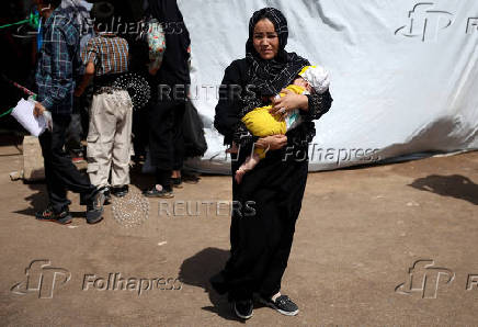 An Afghan woman deported from Iran holds her child at a camp for returning migrants near the Islam Qala border crossing