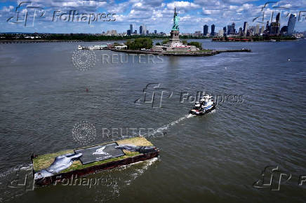 Drone view shows a grass covered barge with painting by Franco-Swiss artist Saype entitled ?Address Hate? towed past Statue of Liberty in New York Harbor