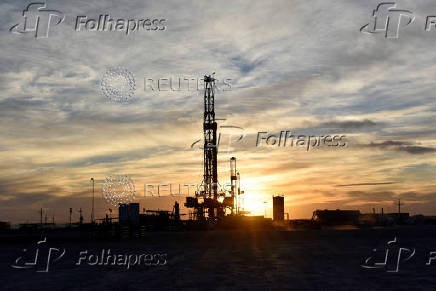 FILE PHOTO: Drilling rigs operate at sunset in Midland