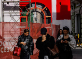 People walk in the street past a construction site of temporary pavilions in Moscow