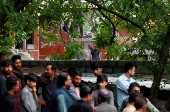 People gather next to a damaged portion of Bilal Mosque after it was hit by an Indian strike in Muzaffarabad