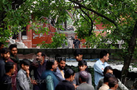People gather next to a damaged portion of Bilal Mosque after it was hit by an Indian strike in Muzaffarabad
