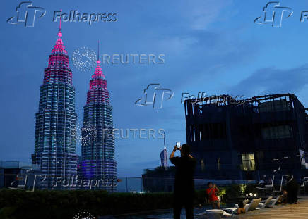 A man takes photos of the Petronas Twin Tower in Kuala Lumpur