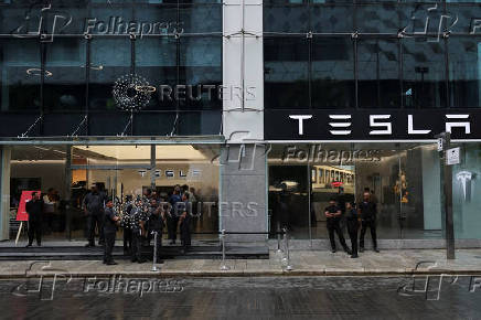 People are seen outside the Tesla showroom ahead of its opening in Mumbai