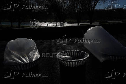 Pedestrians walk near newly emptied trash cans on the National Mall after the longest U.S. government shutdown in history, in Washington