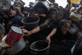 Displaced Palestinians collect donated food in Khan Yunis, southern Gaza