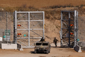 An Israeli soldier closes a gate at the border fence with Gaza