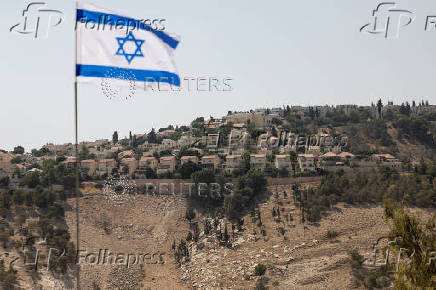 Israeli flag flutters, as part of the Israeli settlement of Maale Adumim is visible in the background, in the Israeli-occupied West Bank