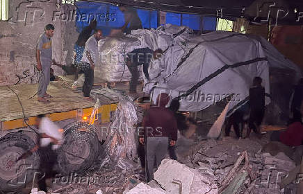 Palestinian workers unload an aid truck, in Khan Younis