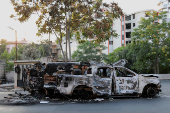 Damaged vehicles remain along a street in Sweida