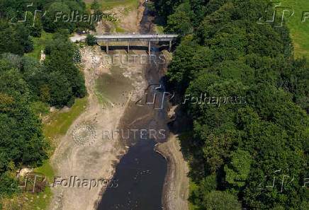 A drone view shows people walking over a bridge across a partially dried section of the Jumbles Reservoir near Blackburn