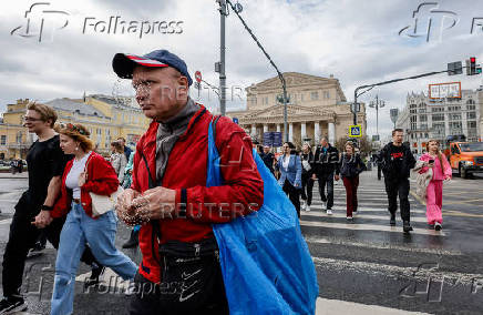 People cross the street in front of the Bolshoi Theatre in Moscow