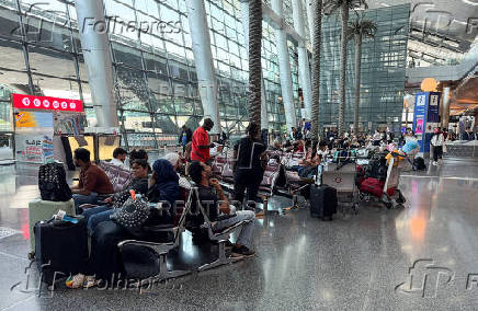 People sit at Hamad International Airport, in Doha