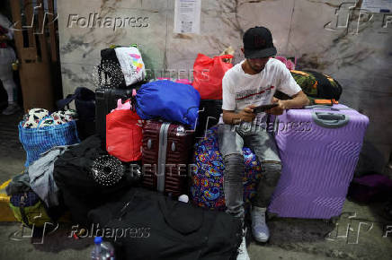 Migrants gather outside the Venezuelan embasssy waiting for a flight back to their country