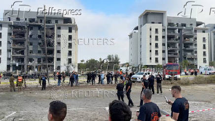 Emergency services officials inspect damage to buildings hit following a missile strike from Iran, in Be'er Sheva