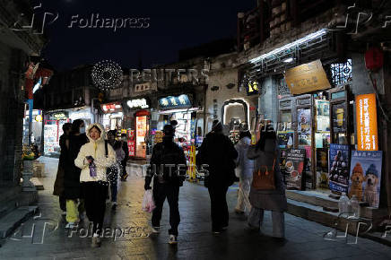 People walk in a commercial street in historical Shichahai district in Beijing