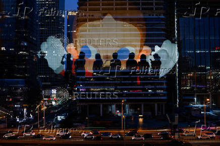 The reflection of silhouettes of people is visible on a glass on a terrace of a shopping mall overlooking Beijing's (CBD)