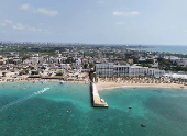 A drone view shows people swimming at a public beach and a private resort in Latakia