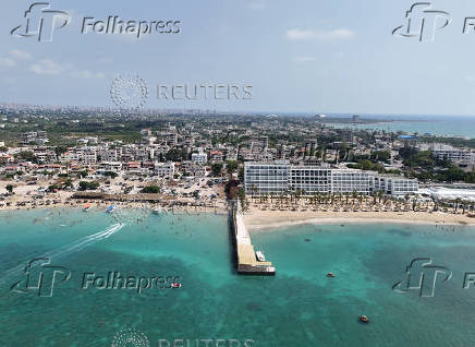 A drone view shows people swimming at a public beach and a private resort in Latakia