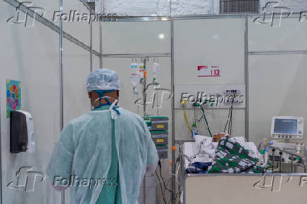Funcionário atende paciente no hospital de campanha do Ibirapuera