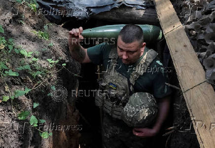 Ukrainian serviceman carries a shell for a self-propelled howitzer before firing towards Russian troops in a front line in Donetsk region