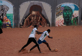 Men play soccer near a graffiti mural in Yoff, neighborhood of Dakar