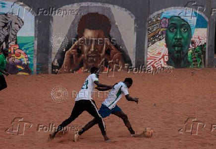 Men play soccer near a graffiti mural in Yoff, neighborhood of Dakar