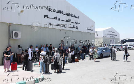 Expats, including diplomats from different nationalities, who were stranded in West Bank and Israel, wait as they hold belongings while being evacuated through the King Hussein Bridge crossing, in South Shuna