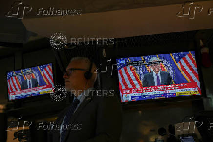 A trader works, as screens broadcast a press conference by U.S. Federal Reserve Chair Jerome Powell following the Fed rate announcement, on the floor of the NYSE in New York