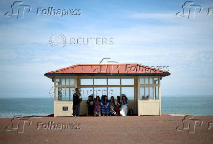Visitors sit inside a shelter on the promenade in Llandudno, Wales