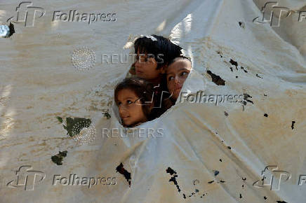 Children from an Afghan family looks outside from a torn tent as they along with their family members prepare to leave, after Pakistan started to deport documented Afghan refugees, in Nowshera