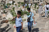 People visit the graves of their relatives at a cemetery, on the first day of the Muslim holiday of Eid al-Adha, in Damascus