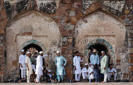 Muslims wait to offer prayers at the ruins of the Feroz Shah Kotla mosque on the occasion of Eid al-Adha, in the old quarters of New Delhi
