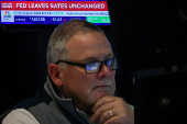 A screen displays the Fed rate announcement as traders work on the floor of the NYSE in New York